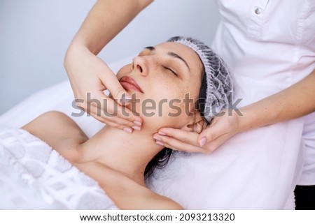Facial massage for a young woman. Cosmetology procedures for face and body skin. Skin care in adulthood. Horizontal photo of people.