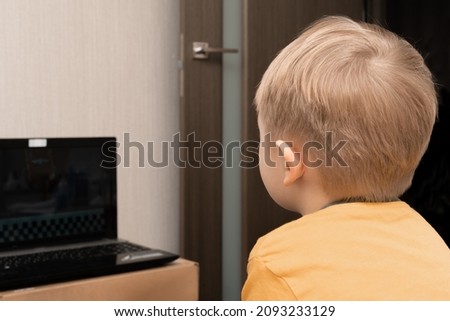 Little boy 3 years old is watching a movie on a laptop screen via the Internet.