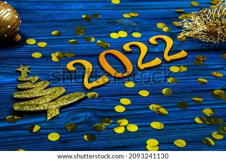 2022 new year, golden numbers on a blue wooden background, many bright sparkles, special blur, focus on numbers, festive background, sparkling tinsel, new year date.
