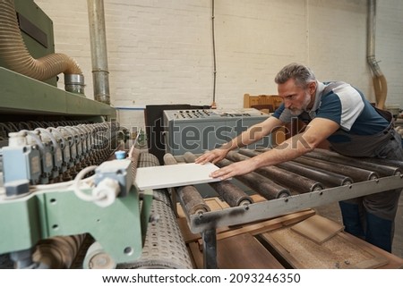 Competent aged carpenter gluing borders of veneer