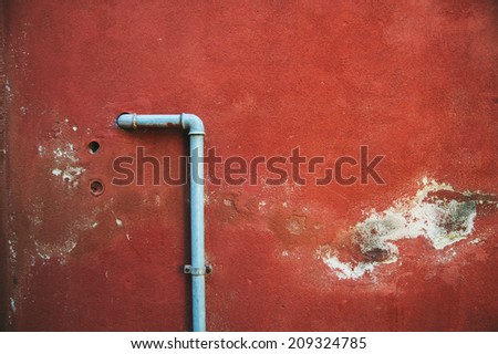 red damaged old wall with a pipe in the middle