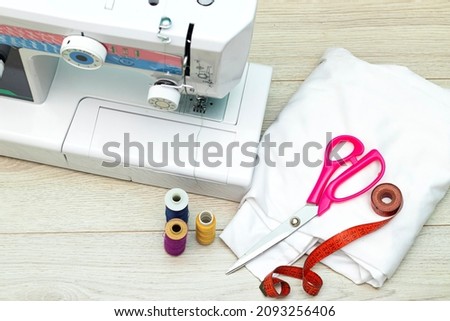 Designer work place sewing machine in office, scissor and colorful bobbins with thread  on wooden table