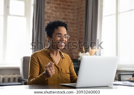 Overjoyed millennial African American woman in eyewear looking at laptop screen, celebrating getting email with amazing news, getting online lottery gambling win notification or dream job offer. Royalty-Free Stock Photo #2093260003