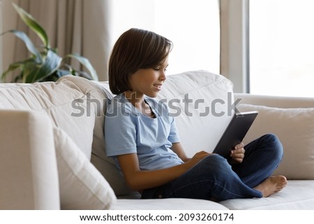Addicted to modern technology happy little preteen kid boy using applications on digital touchpad gadget, web surfing information, playing entertaining games or watching video in social network.