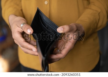 Close up young African American unemployed woman holding opened empty black leather wallet. feeling stressed without cash, having financial problems, suffering from lack of money, bankruptcy concept. Royalty-Free Stock Photo #2093260351