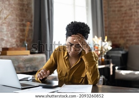 Unhappy frustrated young African American woman feeling stressed managing financial affairs or mistakes, suffering from lack of money calculating business expenditures, accounting, bankruptcy concept. Royalty-Free Stock Photo #2093260852