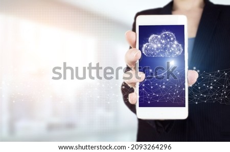 Hand hold white smartphone with digital hologram cloud, download, data sign on light blurred background. Download Data Storage Business Technology Network Concept.