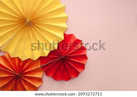 Party festive background. Colorful paper fans over pink background.