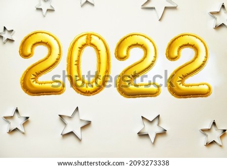 Balloons made of gold foil 2022 on a white background. Metallic shapes of stars.The concept of holidays.Christmas and New Year.