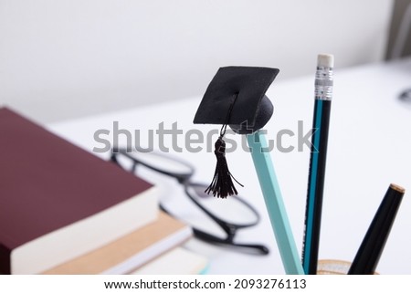 Graduate hat on a pencil on the background of a desktop with office supplies. Online home learning