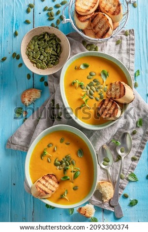 Vegan pumpkin soup with toasted bread and pumpkin seeds. Pumpkin soup with crostini and seeds.
