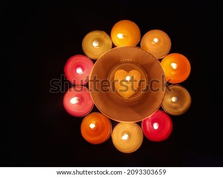 Candle symbols, multicolored circle candles are lit and arranged around a plate with a heart-shaped candle in the center, meaning keeping the heart warm and happy. 