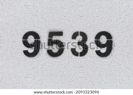 Black Number 9539 on the white wall. Spray paint. Number nine thousand five hundred thirty nine.