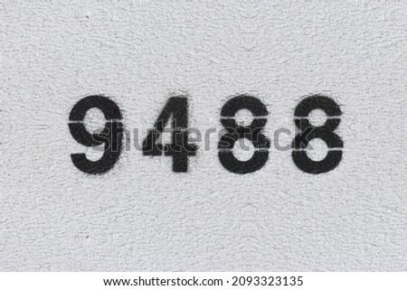 Black Number 9488 on the white wall. Spray paint. Number nine thousand four hundred and eighty.