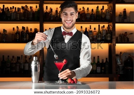 Young barman serving a cocktail at night club. High quality photo Royalty-Free Stock Photo #2093326072