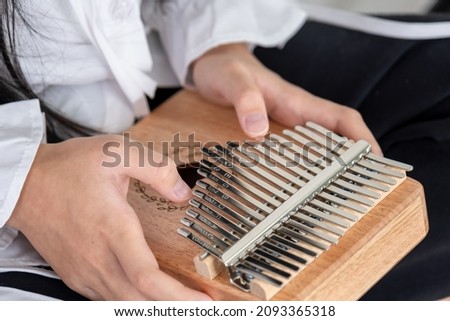 Hand of an Asian girl playing a wooden Kalimba instrument