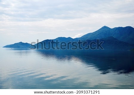 Calm tranquil blue lake on the edge of the mountains range. Scenic nature backgrounds