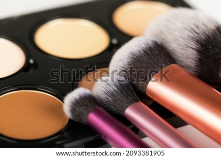 Close up picture of make up products and accessories, contour palette, brushes on white background