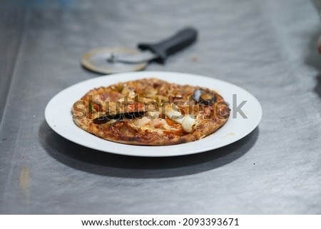 Hot seashell pizza shrimp and tomatoes on white plate