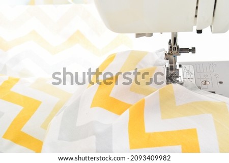 Modern sewing machine and yellow fabric in zigzag. Sewing and home needlework. Flat layout, copy space, close-up, banner, layout
