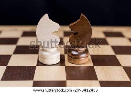 Two chess knights are facing each other on the chessboard. The concept of rivalry, duel, battle, struggle, two opposing sides, enemies, opposition, enmity. Royalty-Free Stock Photo #2093412433