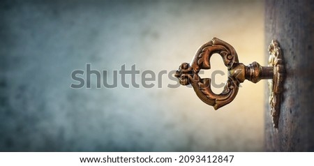 An old key in a keyhole on vintage background, macro photography. Retro style. The key to knowledge. Concept and idea for history, education, business, security, secret background.