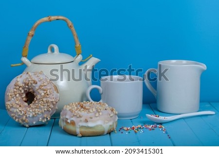 Coffee in a white mug and donuts on a blue background. Tasty breakfast.