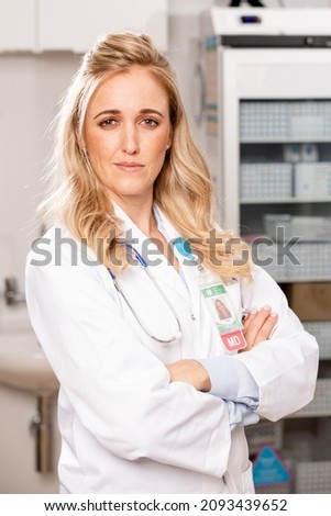 A Portrait of a Young Female Medical Doctor with Protective Surgical Mask, Lab Coat and Stethoscope in a Hospital or Health Clinic. Mid Shot.