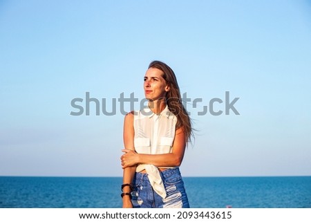 Beautiful young woman in denim shorts and shirt at the sea 