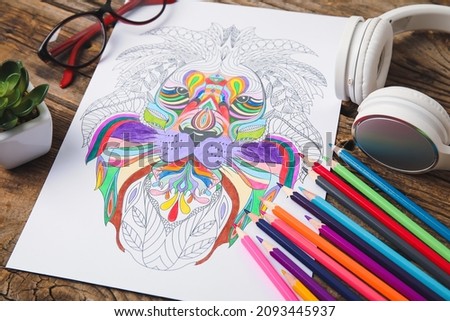 Coloring picture, headphones, glasses and pencils on wooden background