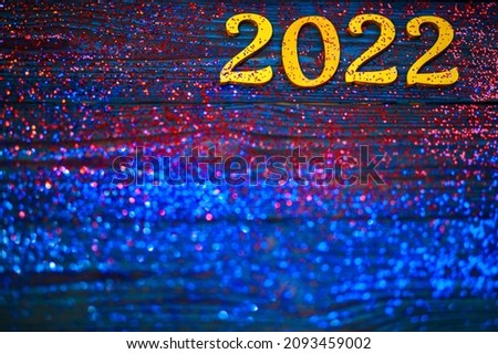 2022 new year, golden numbers on a blue wooden background, many bright sparkles, special blur, focus on numbers, festive background, sparkling tinsel, new year date.
