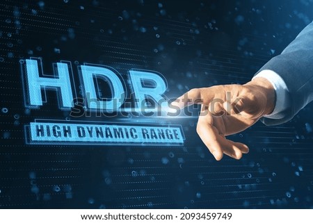 Close up of businessman hand pointing at abstract glowing HDR hologram on blue background. High recolution technology concept