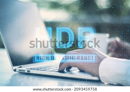 Close up of businessman hands using laptop on desktop with abstract golowing HDR hologram, Blurry background. Technology and display quality concept. Double exposure