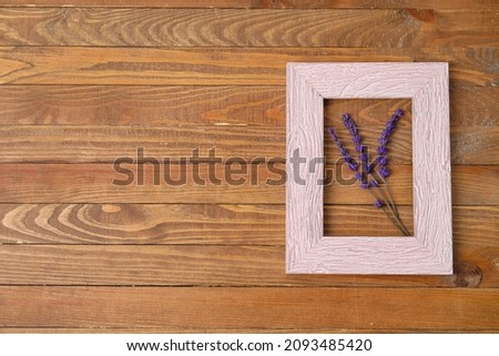 Beautiful lavender flowers and empty picture frame on wooden background