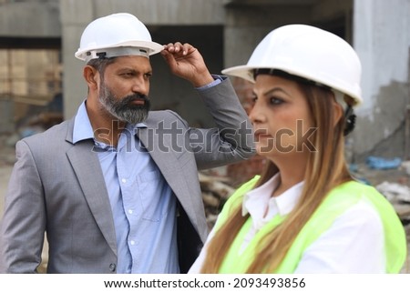 Close up portraits of Construction engineers working together wearing helmets on the construction site. Engineers showcasing the work in progress.
