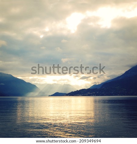Silver linings in Lake Como at the sunset - instagram effect. View of Lago di Como, Italy - retro photo filter. Sunset view of the lake - vintage colors. Varenna, Lake Como, Italy.