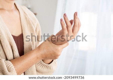 woman suffering from wrist pain, numbness, or Carpal tunnel syndrome hand holding her ache joint  Royalty-Free Stock Photo #2093499736