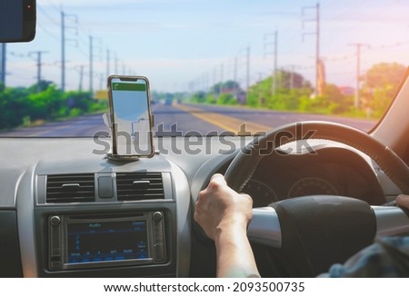 Car driver using smartphone with GPS map navigation application while driving on highway, view from inside car Royalty-Free Stock Photo #2093500735