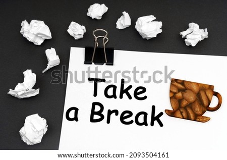 Rest at work. On the black surface is a white sheet with the inscription - Take a Break, a cup with a picture of coffee beans.
