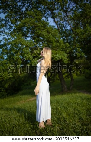 Portrait of a young woman in a beautiful white dress in a green summer park. Image with selective focus, noise effects and toning. Focus on the girl