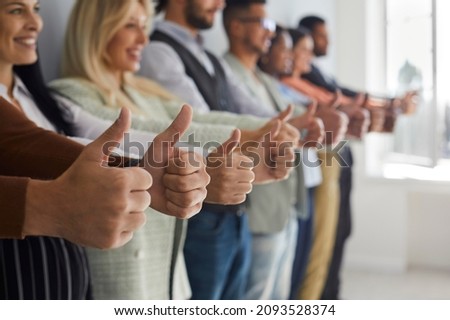 Row of happy successful young modern business people giving thumbs up. Team of many confident businessmen, businesswomen and company workers smiling and showing 'like' or 'excellent job' sign together