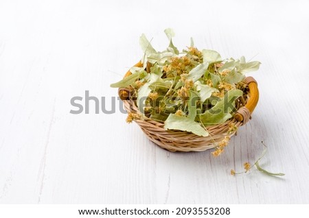 Dried linden leaves and flowers in a wicker basket. Wooden background. Design concept. Selective focus. Royalty-Free Stock Photo #2093553208