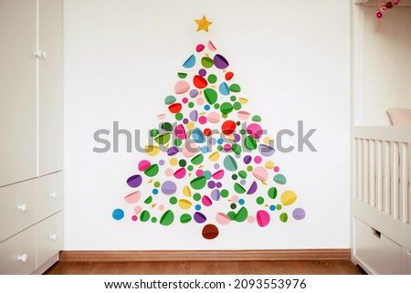 Idea of a Christmas tree with your own hands is hand made of multicolored paper and colored cardboard glued on the wall of the nursery. Children's bedroom interior. Color circles with Very Peri. Xmas