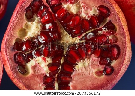 Sliced pomegranate fruits with juicy seeds on blue background
