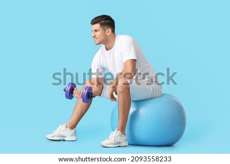 Sporty young man training with dumbbell on color background Royalty-Free Stock Photo #2093558233