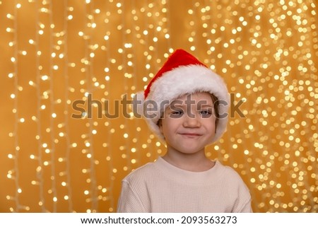 Portrait of cute child with Santa Clause hat smiling at bokeh background