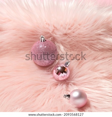 Creative layout with three pink Christmas baubles on pastel pink faux fur background. 80s or 90s retro fashion aesthetic concept. Minimal New Year or Christmas celebration idea.