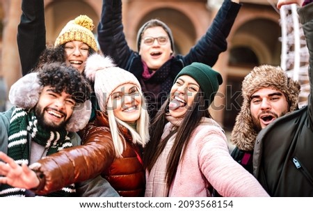 Multicultural guys and girls taking selfie on warm fashion clothes - Happy life style concept with milenial people having fun together outdoors on winter holidays - Warm contrast filter