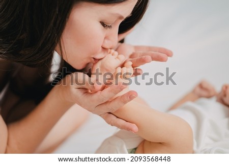 a gentle and loving mother kisses the baby's legs. the happiness of motherhood. vitamins and cosmetics for mother and child.
