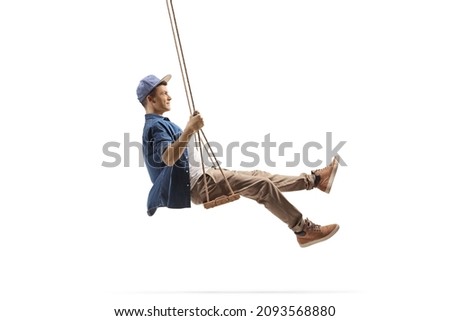 Profile shot of a young man swinging on a wooden swing isolated on white background